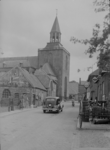 103 Tubbergen: Opname van een straat in het dorp, met kerk, de zestiende-eeuwse basiliek, op de achtergrond. Op straat ...