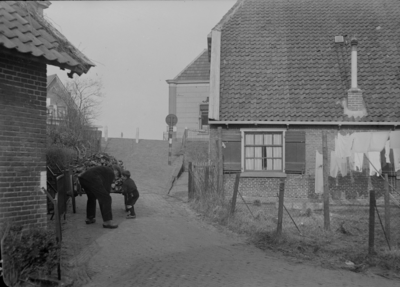 115 Wijhe: Opname van een man met kind op een erf tussen een paar huizen., 12-02-1941