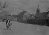 87 Olst: Opname van een straat in het dorp, met huizen en een fietser, en de kerk op de achtergrond., 1941-04-04