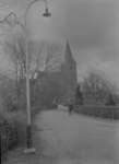 89 Olst: Opname van een straat in het dorp, met huizen en de Willibrorduskerk (hervormde kerk) op de achtergrond. Er ...