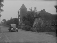 96 Staphorst: Opname van een straat in het dorp, met daaraan een kerk en een boerderij. Er rijdt een auto over straat., ...