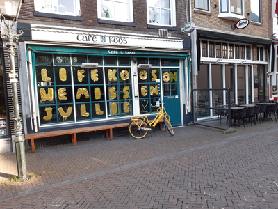 368 Bericht in goudkleurige letters op de ruit van Café Koos aan de Nieuwe Markt in Zwolle: 'Life Koos On. We missen ...