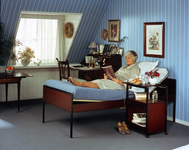 385 Reclamefoto van een senioren-bed model Carelle met bijpassend nachtkastje met uitschuifbaar tafelblad. Gebruikt in ...