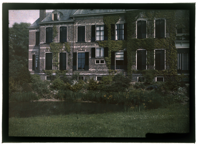 77 Glaspositief in kleur (autochrome): Landhuis met klimop, grasveldje met water op de voorgrond, 1920-06-20