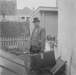 1280 Sam Noach in pak met hoed op en met een koffer in de hand, op een dakterras.