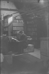 112 Man met lange baard, Dr. Koenraad Oege Meinsma, leest een boek op een zolder met boekenkasten., 1875-01-01