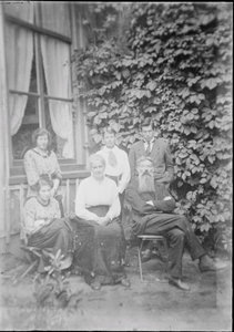 94 Groepsportret. Gezin met vader, moeder en vier kinderen poseert in tuin. Man met lange baard is Koenraad Oege ...