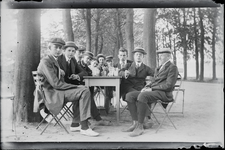 101 Gezelschap van jongemannen zittend aan tafel buiten tussen de bomen, 1910-01-01