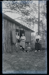 109 Groepsportret van vier meisjes, met tennisrackets, poserend buiten bij een houten huisje., 1912-04-20