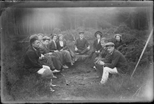 113 Groepsportret buiten in het bos van een grote groep jongedames en jongemannen, allen zittend., 1910-01-01