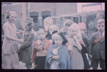 349 Bevrijdingsfeest mei 1945 in de Sint Jurriënstraat, met een kinderoptocht; kinderen zijn verkleed, vlaggen hangen ...