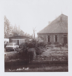 WAT001001397 Stolpboerderij De Kameleon Dorpsstraat 60 te Jisp, met aan de linker kant de garage van nummer 62.