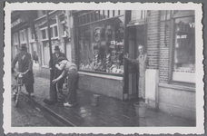 WAT001003375 Maarten Sanders, staande in de deuropening van zijn winkel aan de westzijde van de Koemarkt.