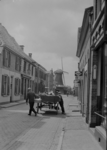 107 Wijhe: Opname van een paard met wagen in de Langstraat, met huizen en een molen op de achtergrond, dit is de ...