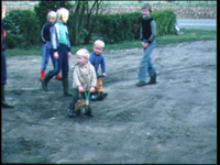 13867BB00326 Familiefilm Olthof.Een groep kleine kinderen speelt op een drassig veldje in de straat. Ze poseren en ...