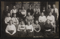 1034 Twintig vrouwen, leerlingen en leraressen aan de Vrouwenarbeidschool, afdeling Kostuumnaaien, poseren. Afgedrukt ...