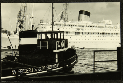 429 Schip genaamd Oranje aangemeerd in de haven van Amsterdam, met op de voorgrond een duwboot van N.V. Rederij ...