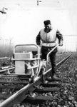 153384 Afbeelding van een baanwerker van de afdeling Wegonderhoud van de N.S. met een kraagschroefmachine op het spoor ...