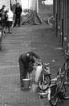 600494 Afbeelding van een man die zijn bromfiets wast in de Boogstraat (Zeven Steegjes) te Utrecht.